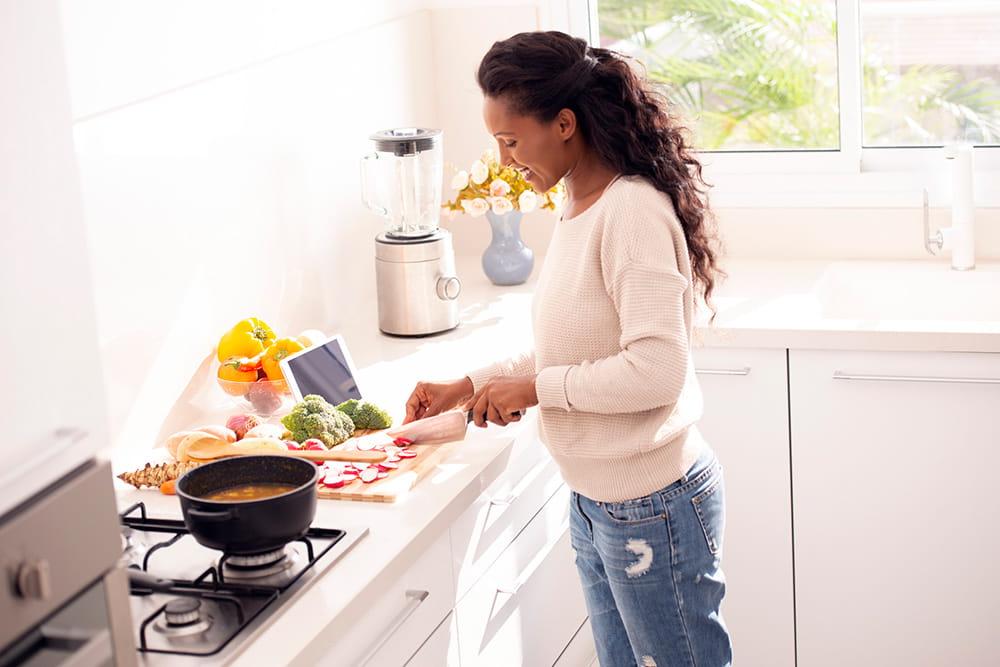 woman chopping food to put in pot on stove