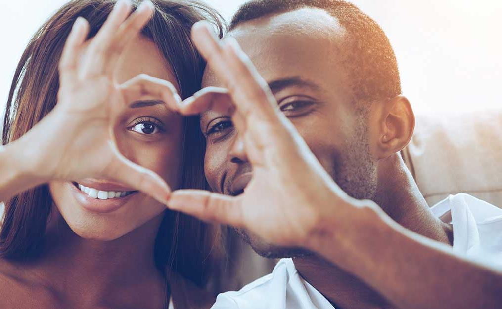 african american couple making heart sign with their hands