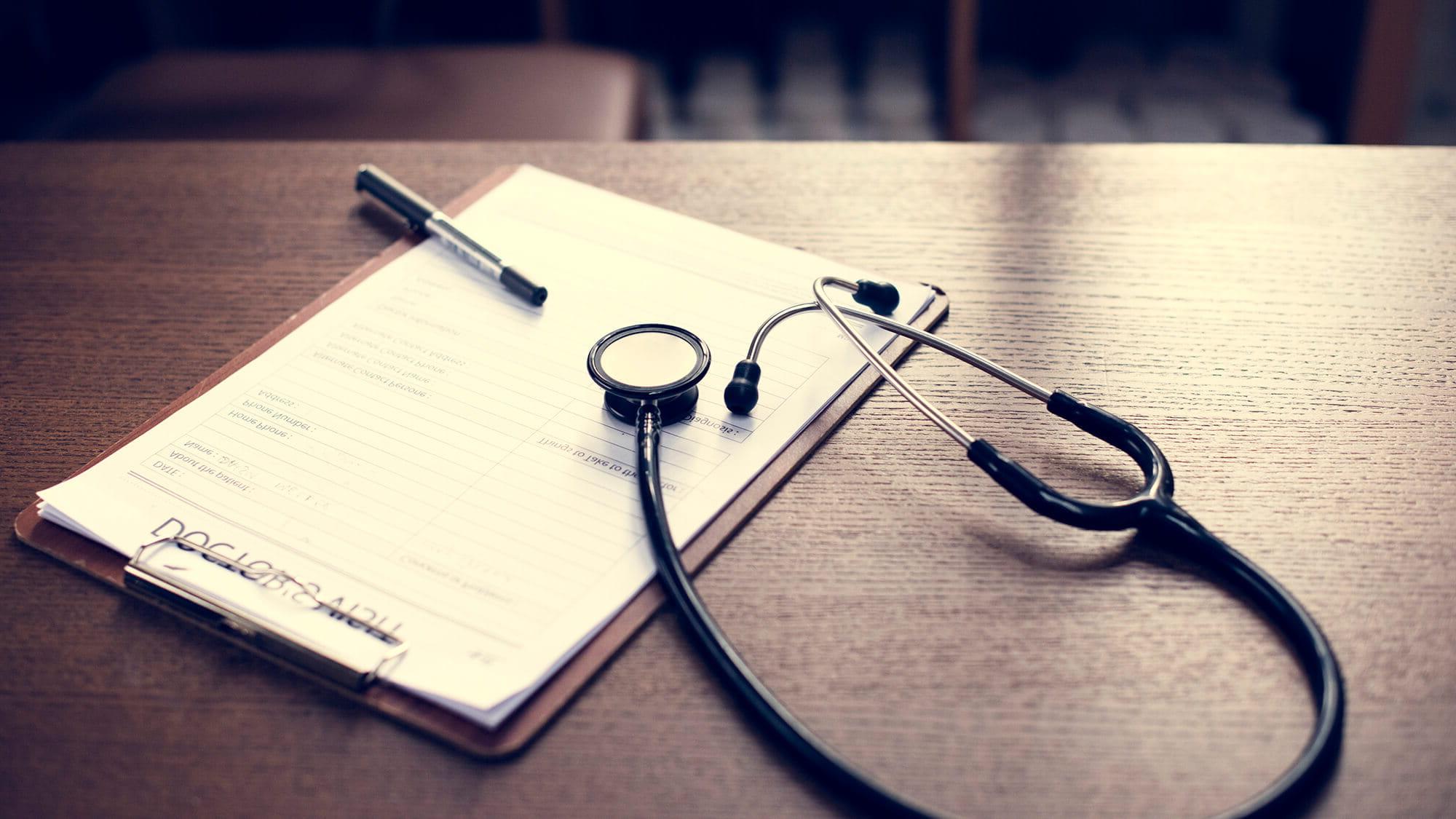 checkup form and stethoscope laying on desk
